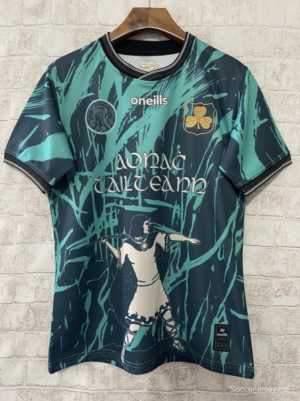 قميص تيبيراري GAA 25/26 تيبيراري GAA باللون الأزرق المخضر مع صورة ظلية للمحارب ونقشة فرشاة مجردة