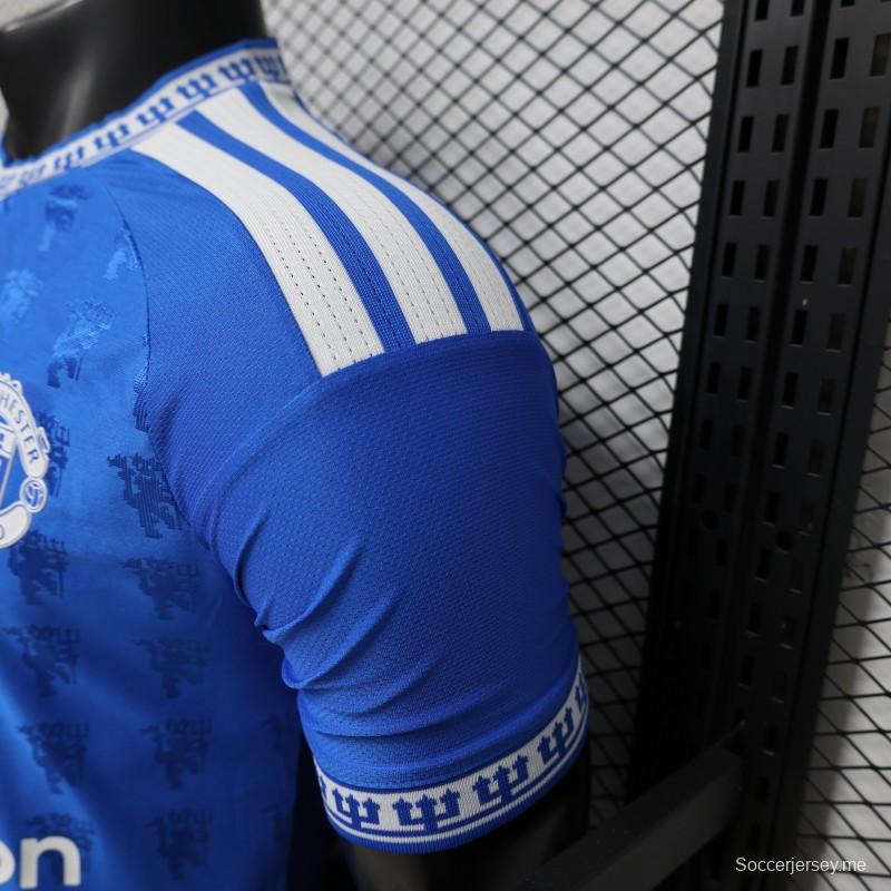 قميص اللاعب نسخة 26/27 باللون الأزرق الخاص بنادي مانشستر يونايتد مع نقشة جاكار على شكل شيطان تغطي كامل القميص