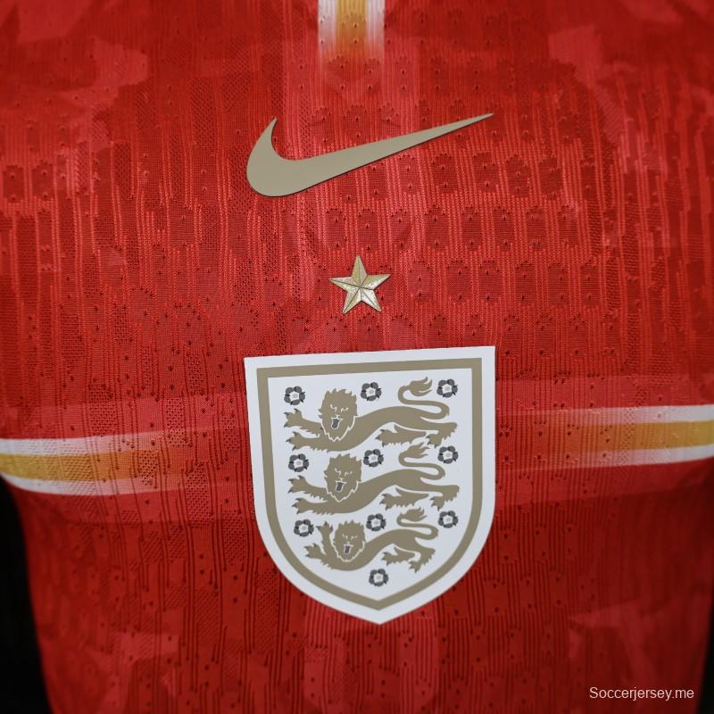 قميص اللاعب الإصدار 2026، قميص إنجلترا خارج أرضها باللون الأحمر مع شعار الأسد الذهبي، إصدار خاص